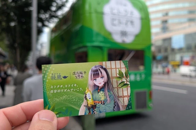 ツアー終了後、綾鷹コラボイラスト入りのCoke ONチケットカードを手に、ヒトクチヒトイキ旅バスを背に記念撮影。旅の余韻が伝わる一枚。