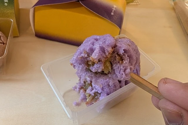『ヒトクチヒトイキ旅』バスツアーで提供された和菓子・芋ふくさを一口サイズにカットし、串で持ち上げた様子。紫色の皮の中に甘い芋あんがのぞいている。