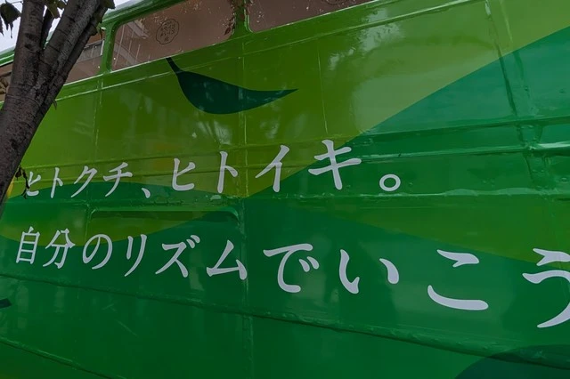 鷹『ヒトクチヒトイキ旅』バスの側面デザイン。1階に窓はなく『ヒトクチ、ヒトイキ。自分のリズムでいこう。』のメッセージが描かれている。