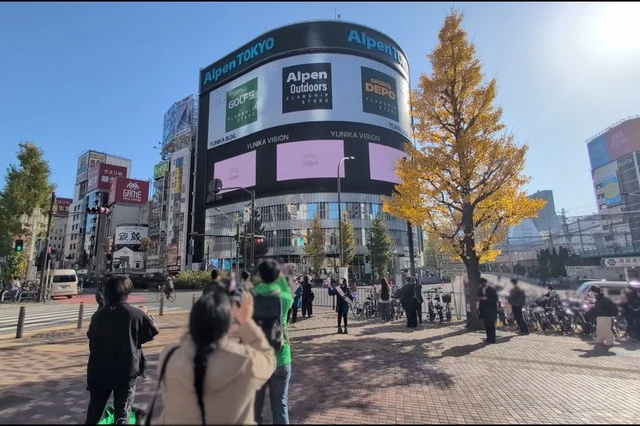 秘密結社holoX × タイミー 新宿ビラ配りの現地レポ
すぐ近くの街頭ビジョンで応援広告が流れるのを待つファン達